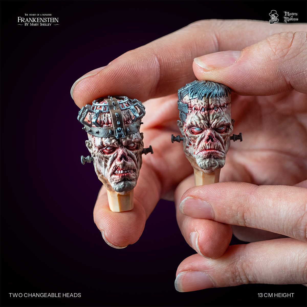 Two interchangeable Frankenstein Creature heads held between fingertips, cage head and grey-haired head | Studio Everart