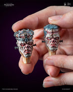 Two interchangeable Frankenstein Creature heads held between fingertips, cage head and grey-haired head | Studio Everart